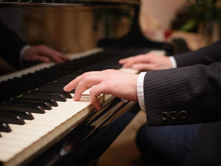 Close up of a piano keyboard with a man's hands playing